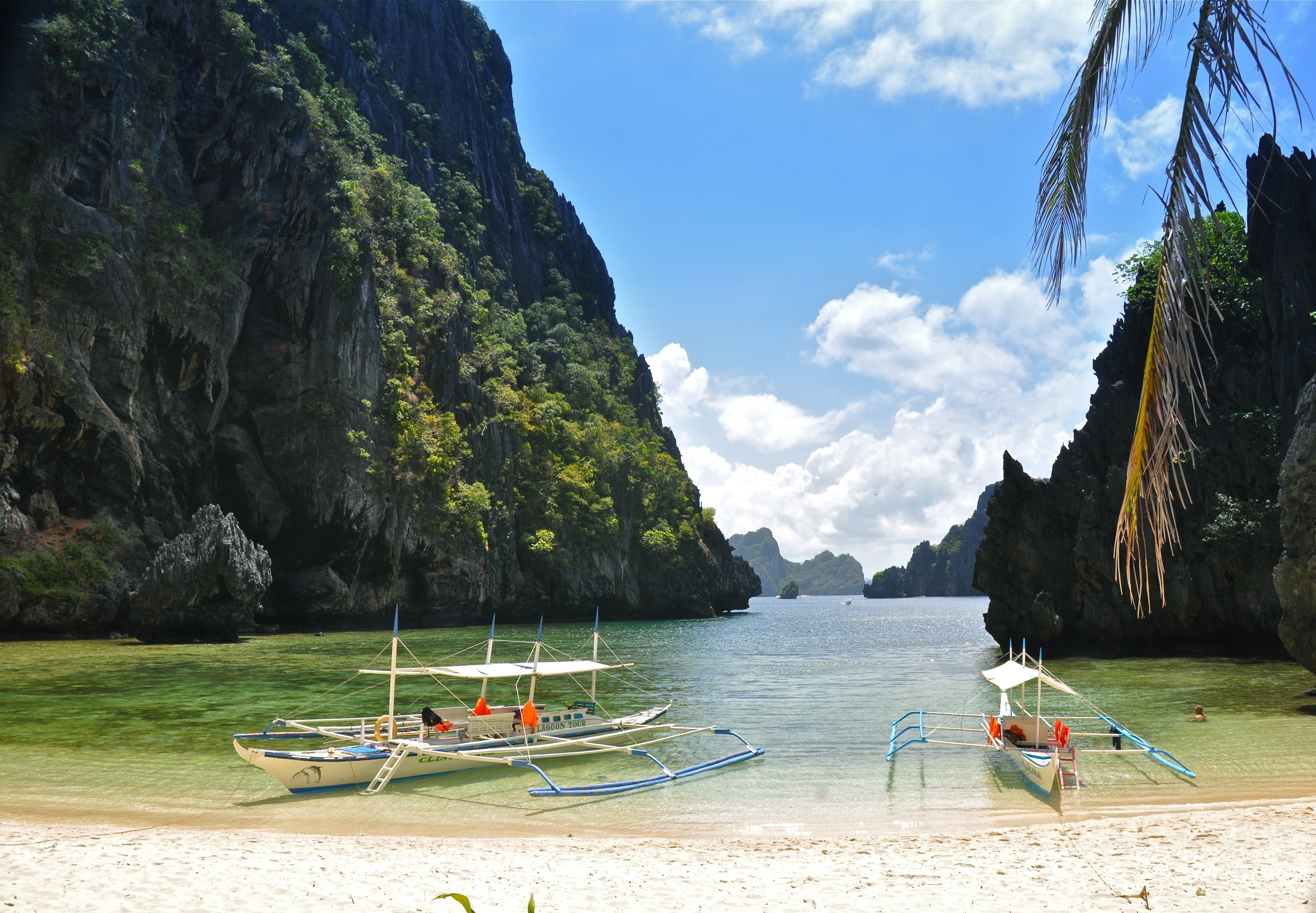 tropical beach with boats and cliffs