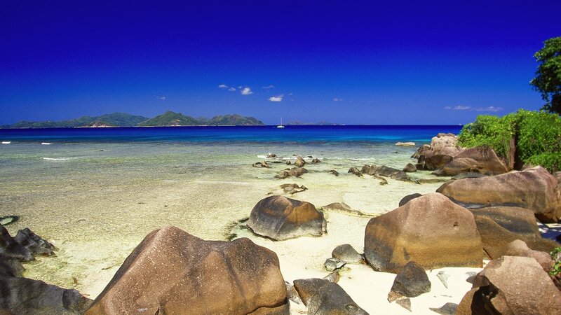 Tropical Beach with Rocks — Blue, Serene, Afternoon, Photograph, Ocean, Island, Sailboat, Green, Brown
