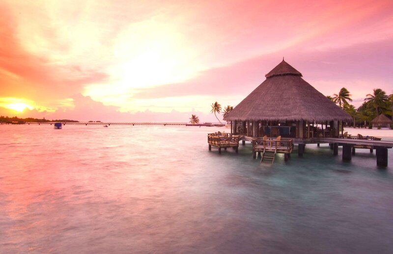 tropical sunset over water bungalow