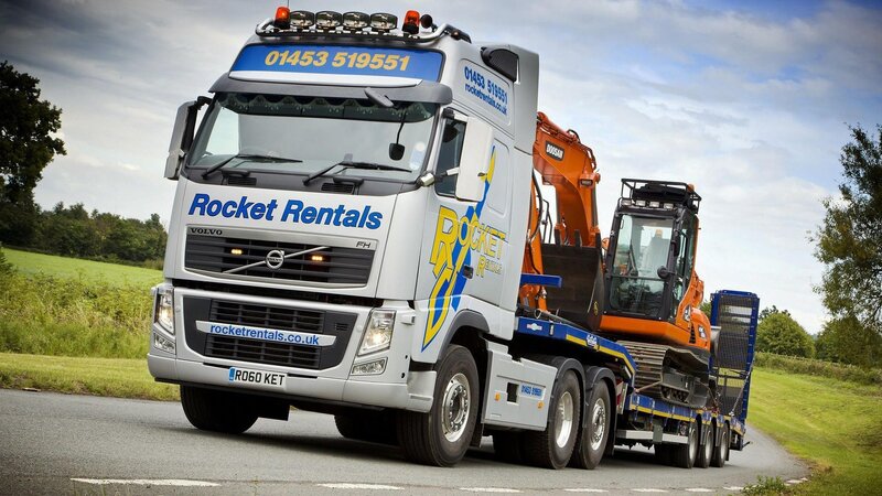 Truck carrying excavator on road