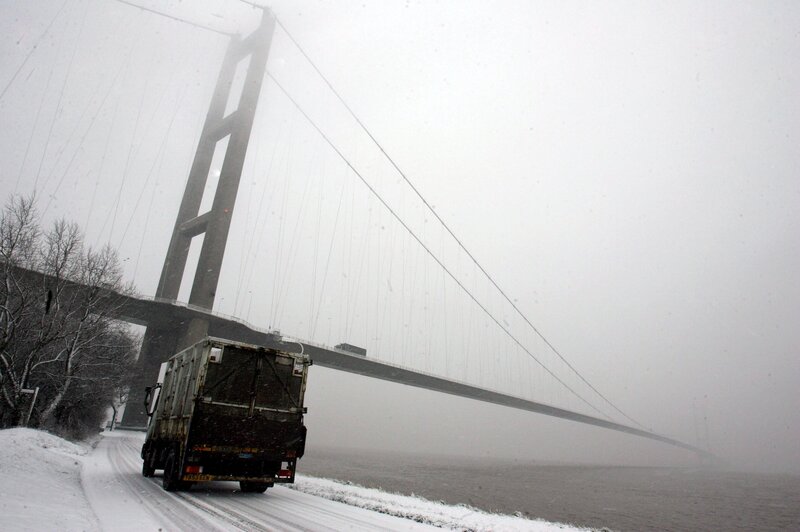 Truck on snowy road near bridge