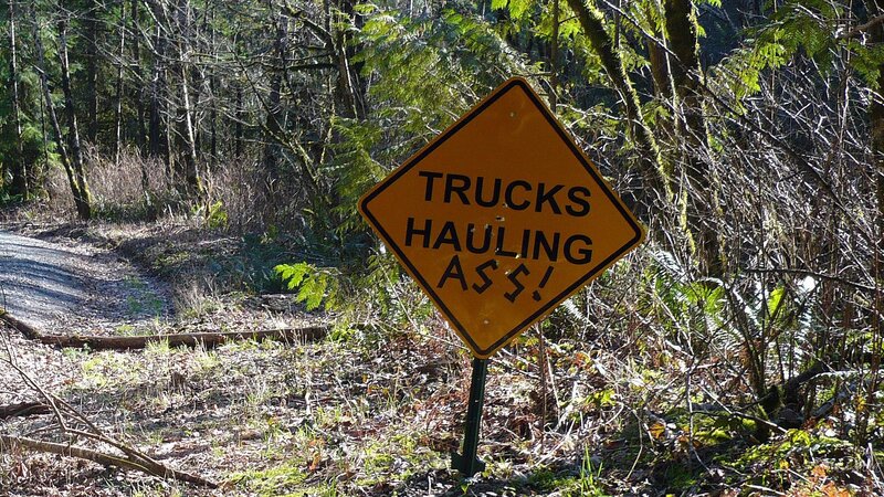 Trucks Hauling Ass sign in forest