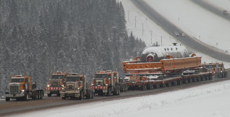 Trucks transporting large object in snow