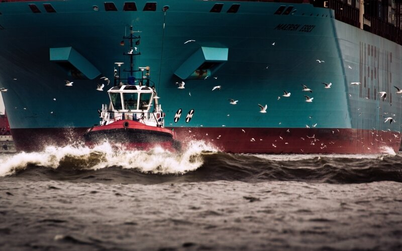 Tugboat assisting large cargo ship