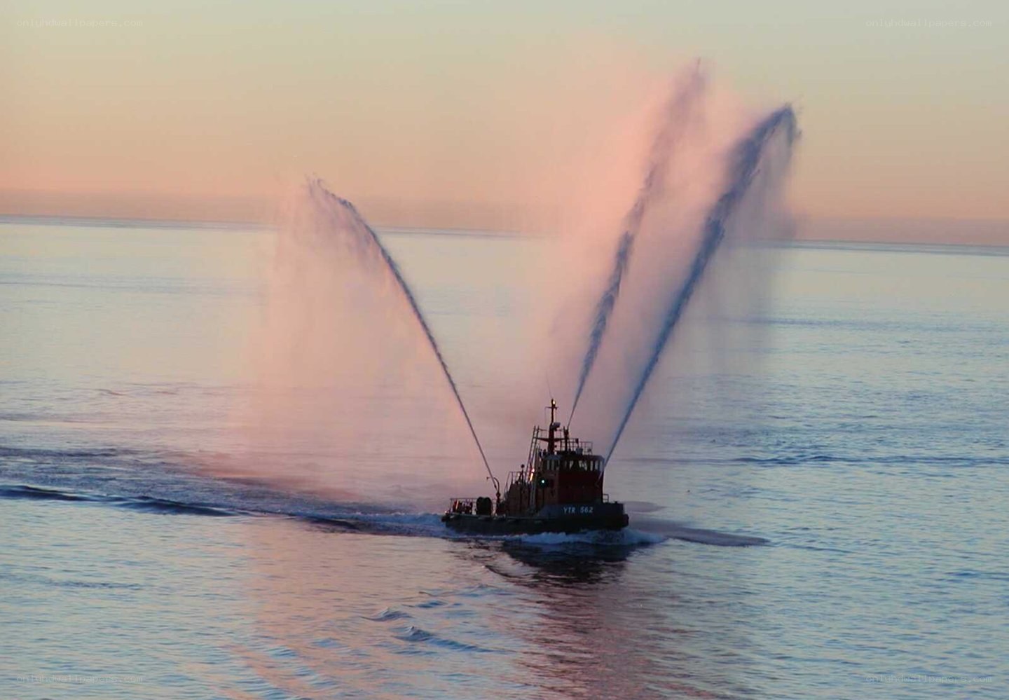 Tugboat spraying water at sunset