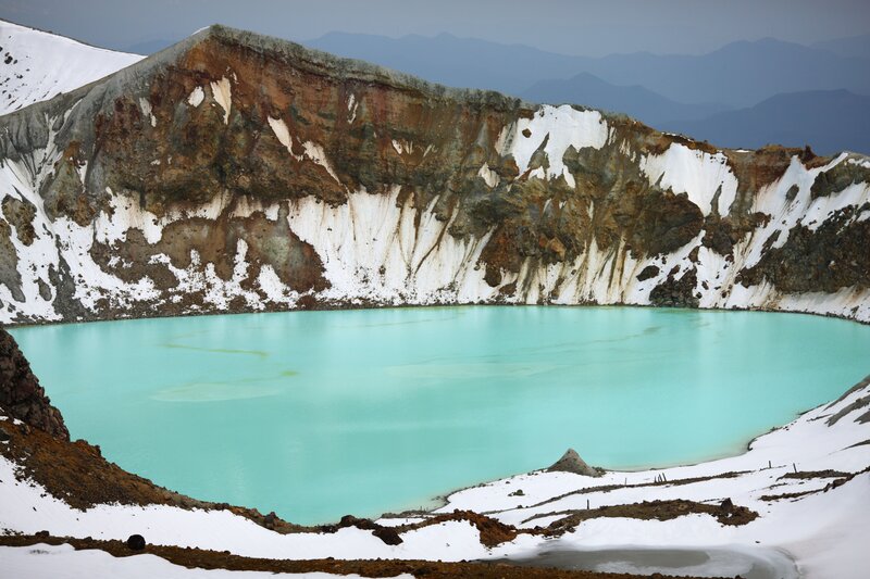 Turquoise crater lake in snow