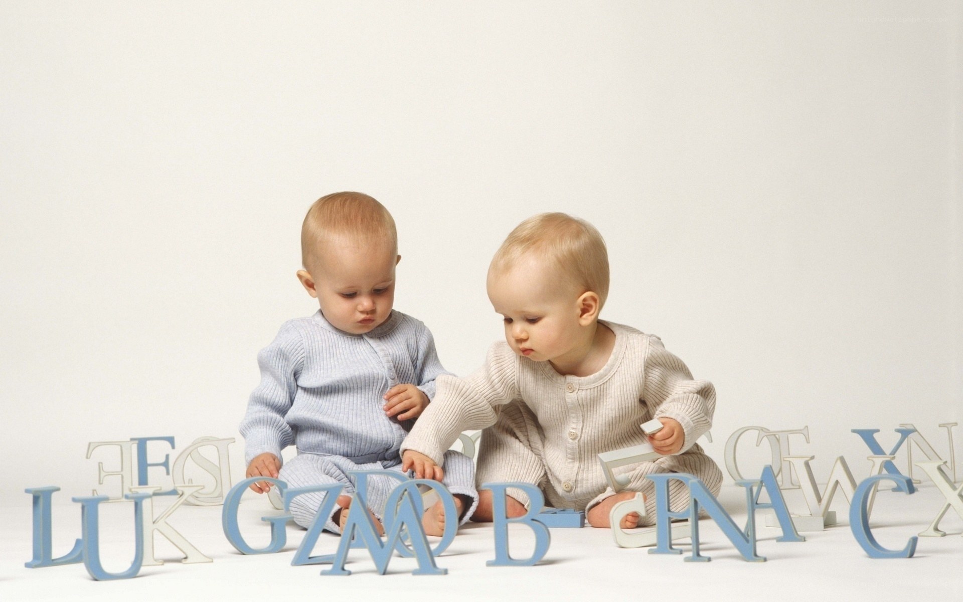 Two babies playing with alphabet blocks