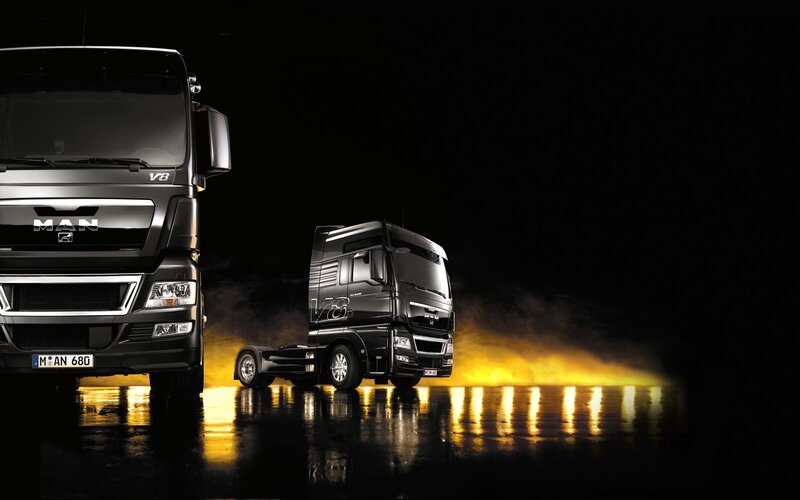 Two black MAN trucks on wet surface