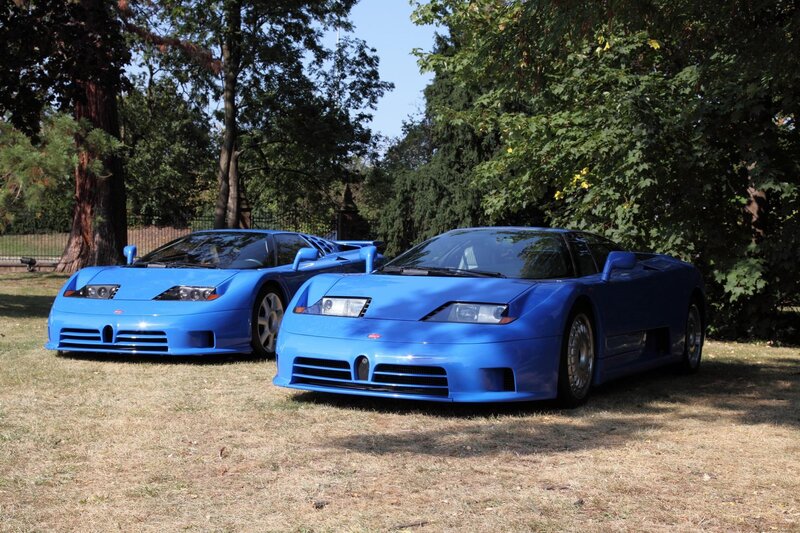 Two blue Bugatti EB110s on grass