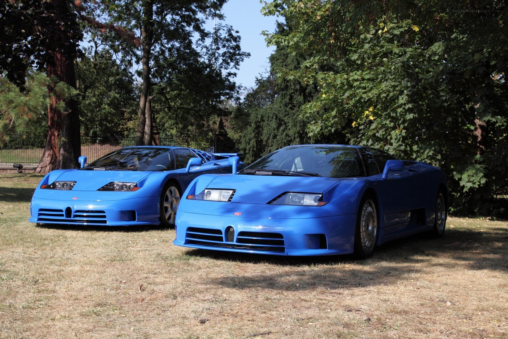 Two blue Bugatti EB110s on grass