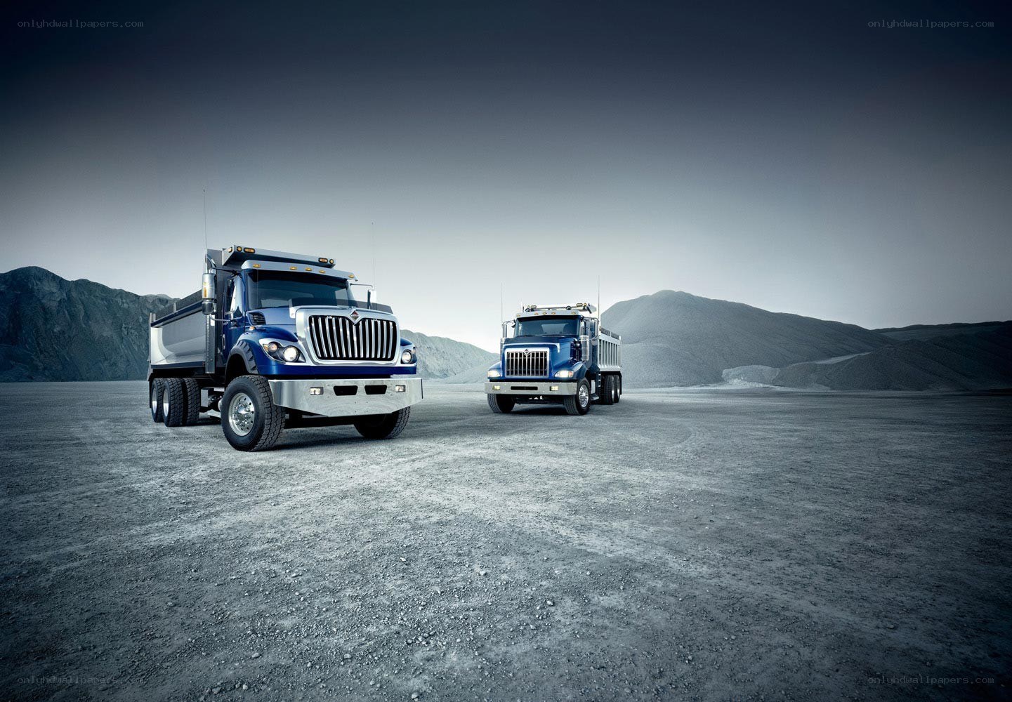 Two blue dump trucks in desert