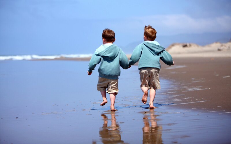 two boys running on the beach