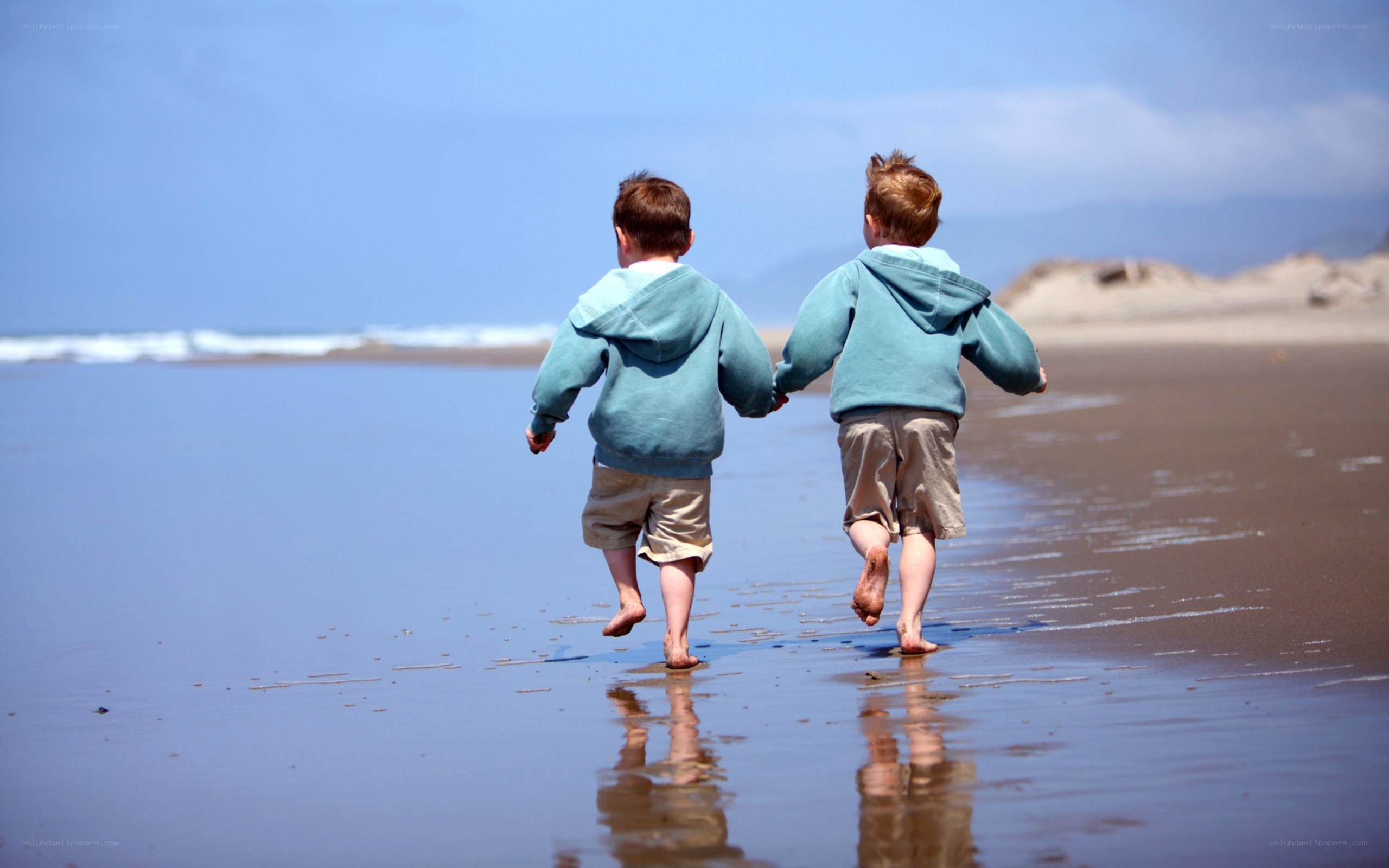 two boys running on the beach