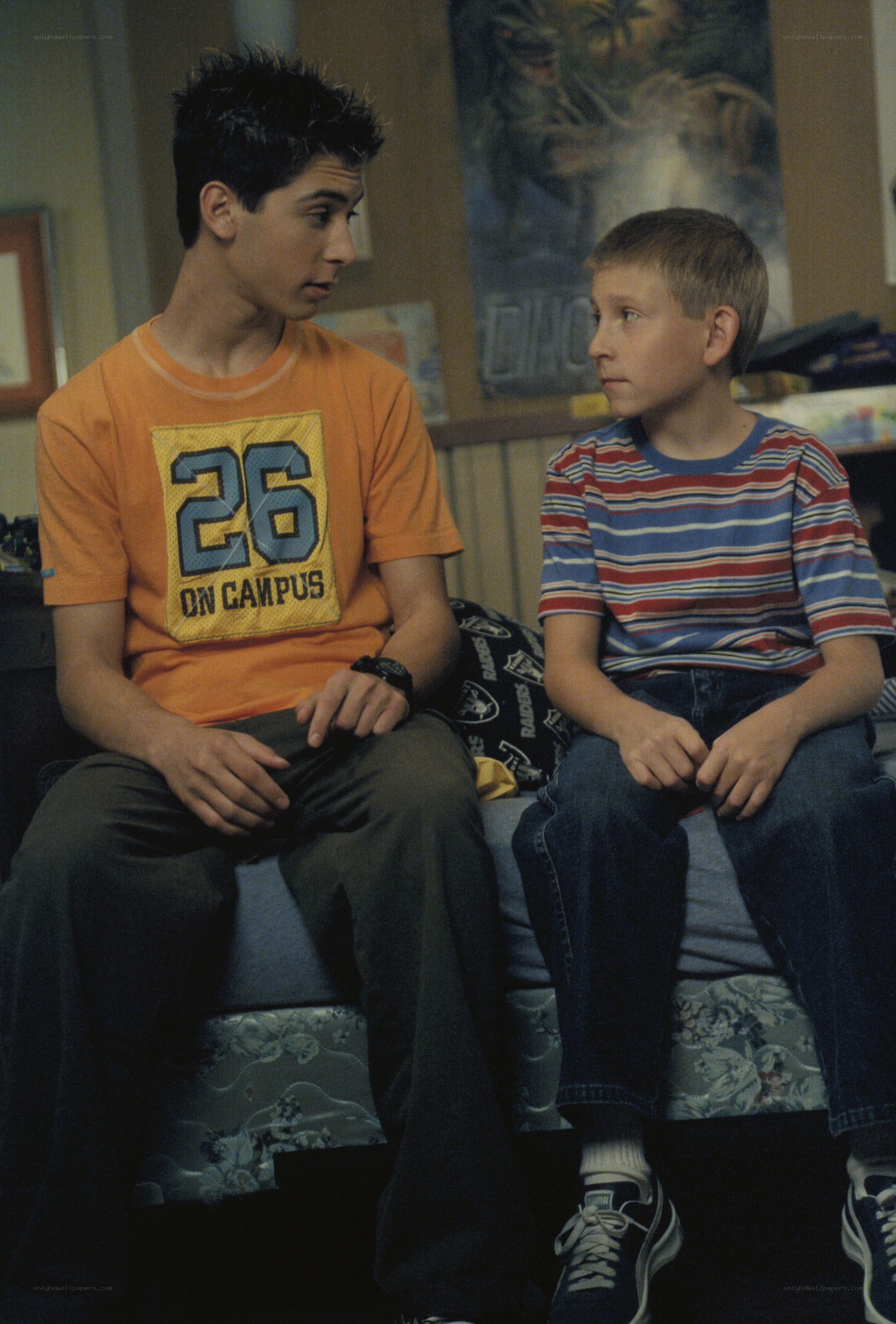 Two boys talking on a bed