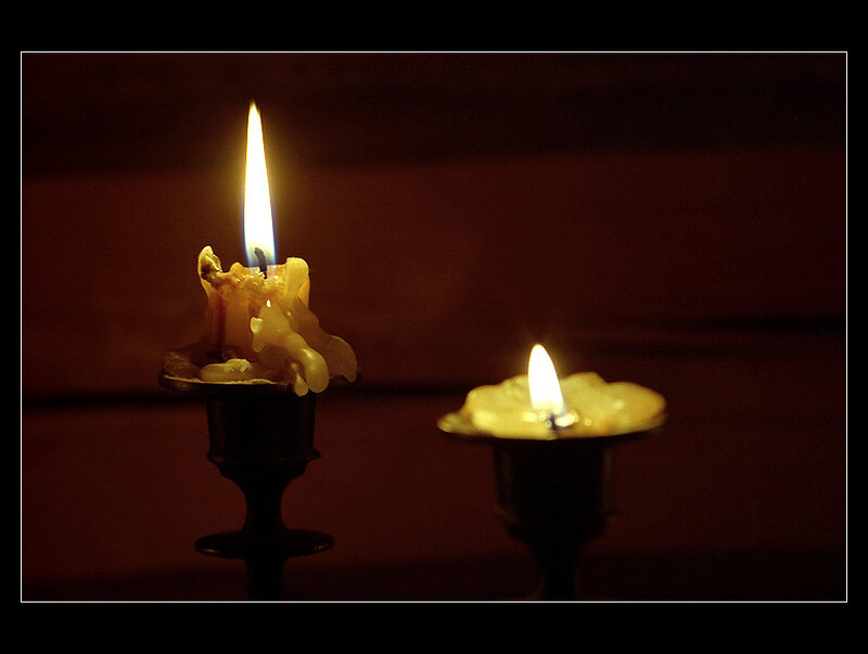 Two candles burning in darkness