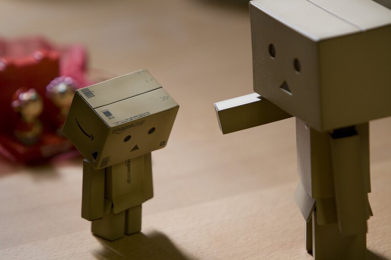 Two cardboard box figures interacting