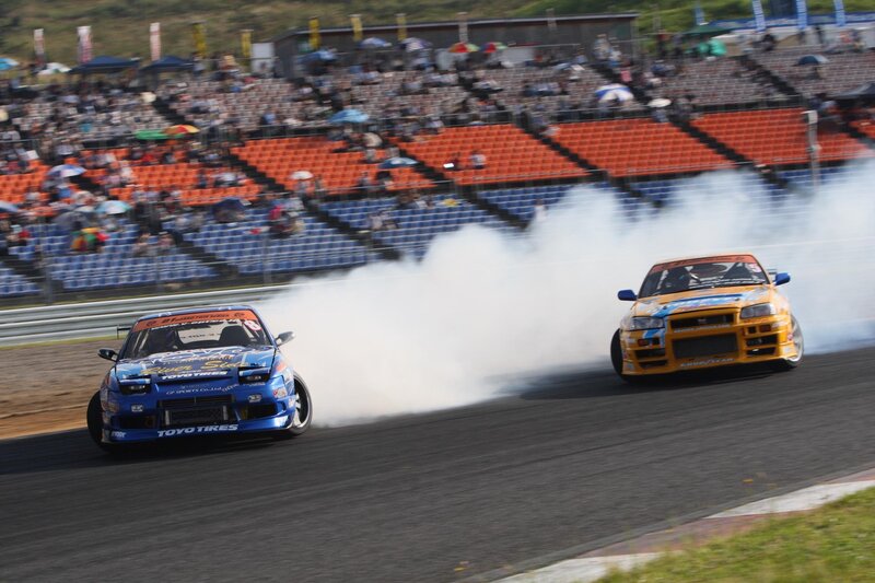 Two cars drifting on a racetrack