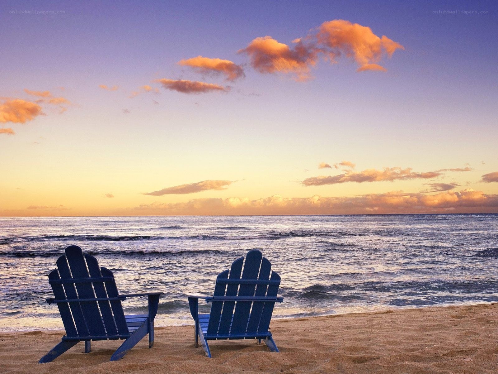 Two chairs on a beach at sunset