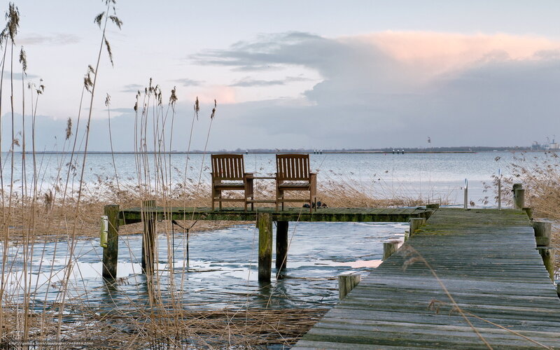 Two chairs on a dock at dusk
