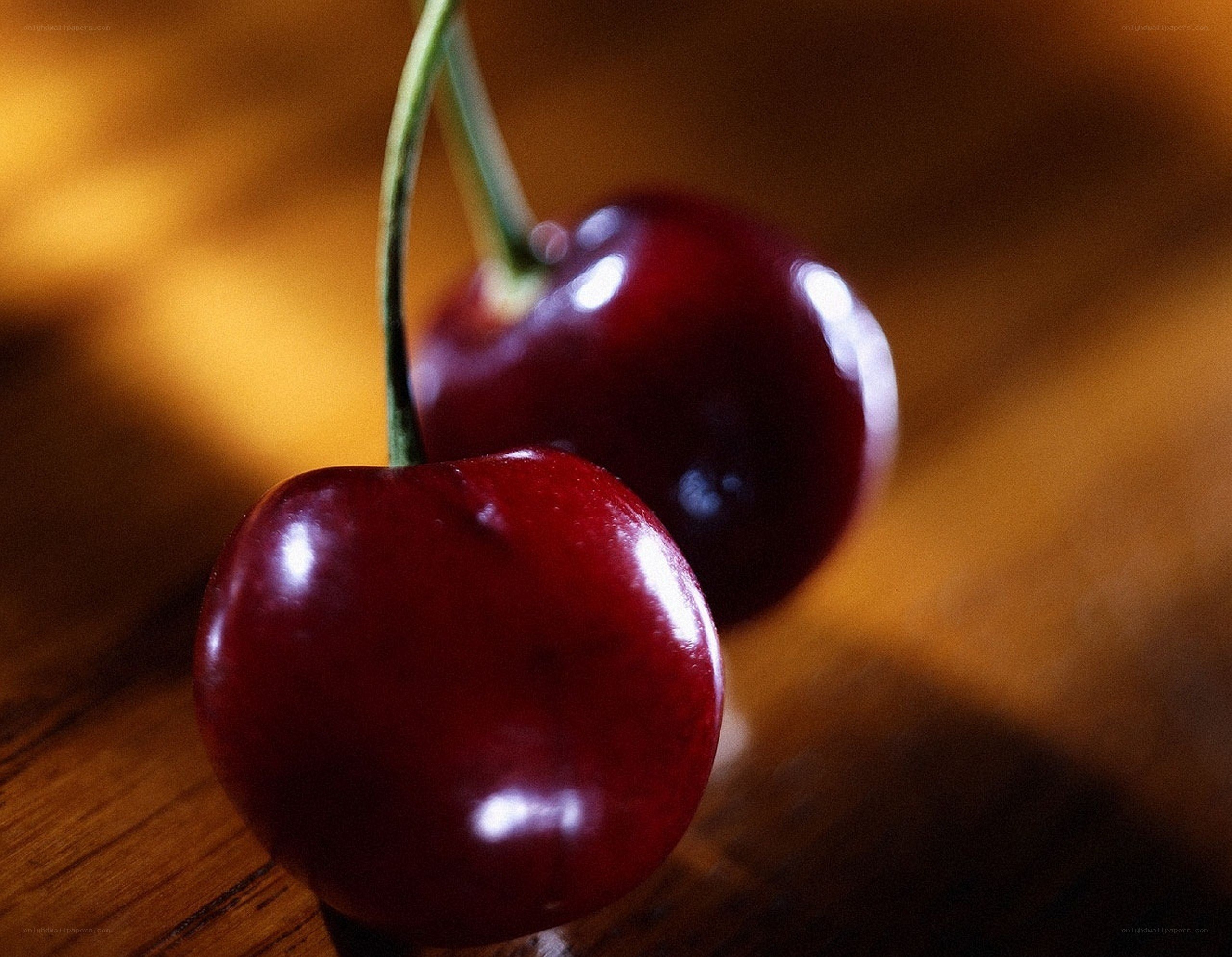 Two cherries on a wooden surface