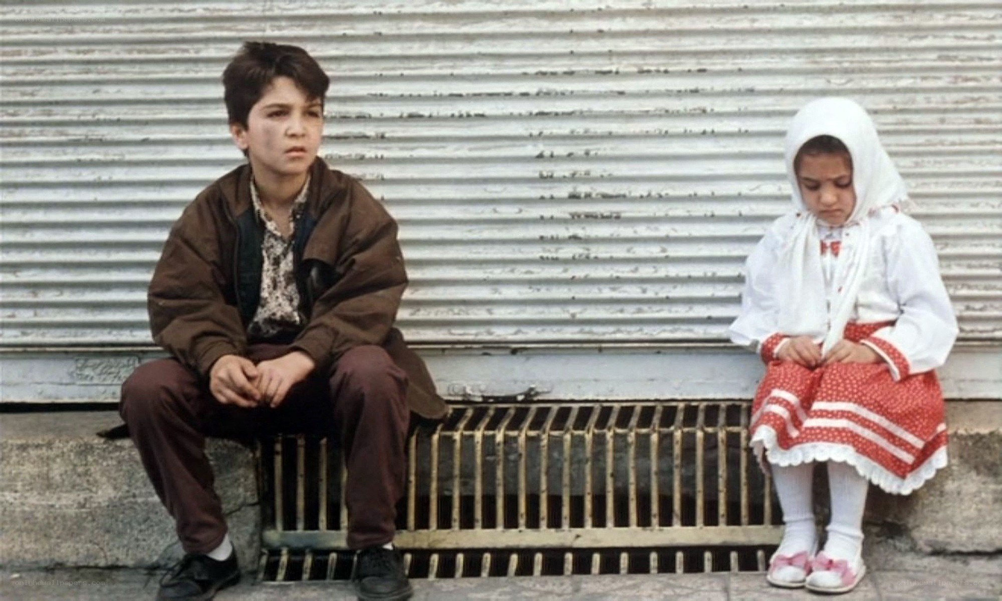 Two children sitting on a curb