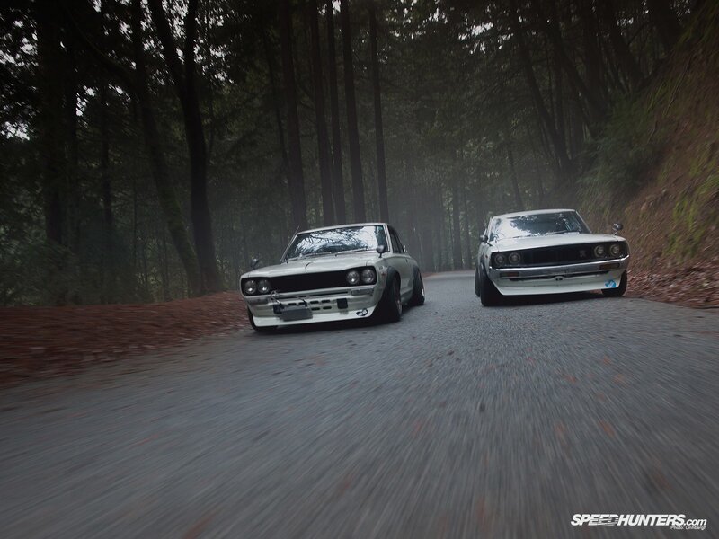 Two classic cars on a forest road