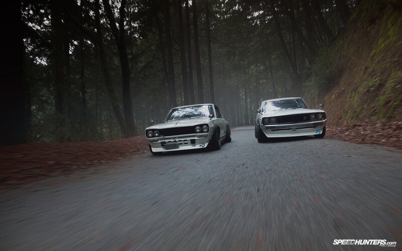 Two classic cars on a forest road