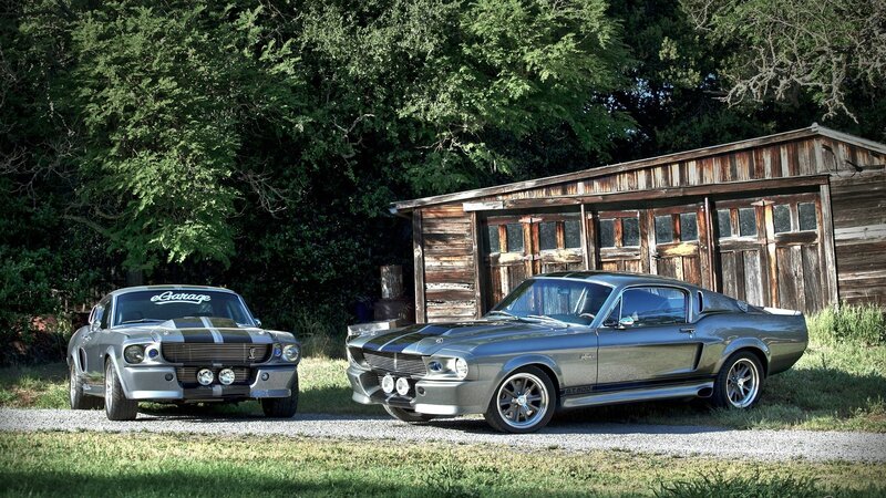 Two classic muscle cars in a yard