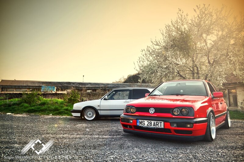 Two classic VW cars in a gravel lot