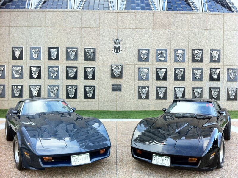 Two Corvettes in front of a wall