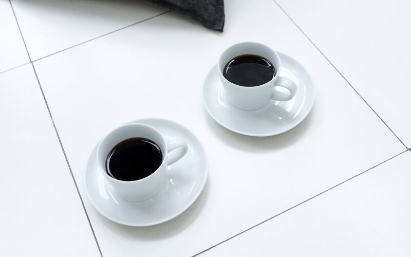 Two cups of coffee on white tiles