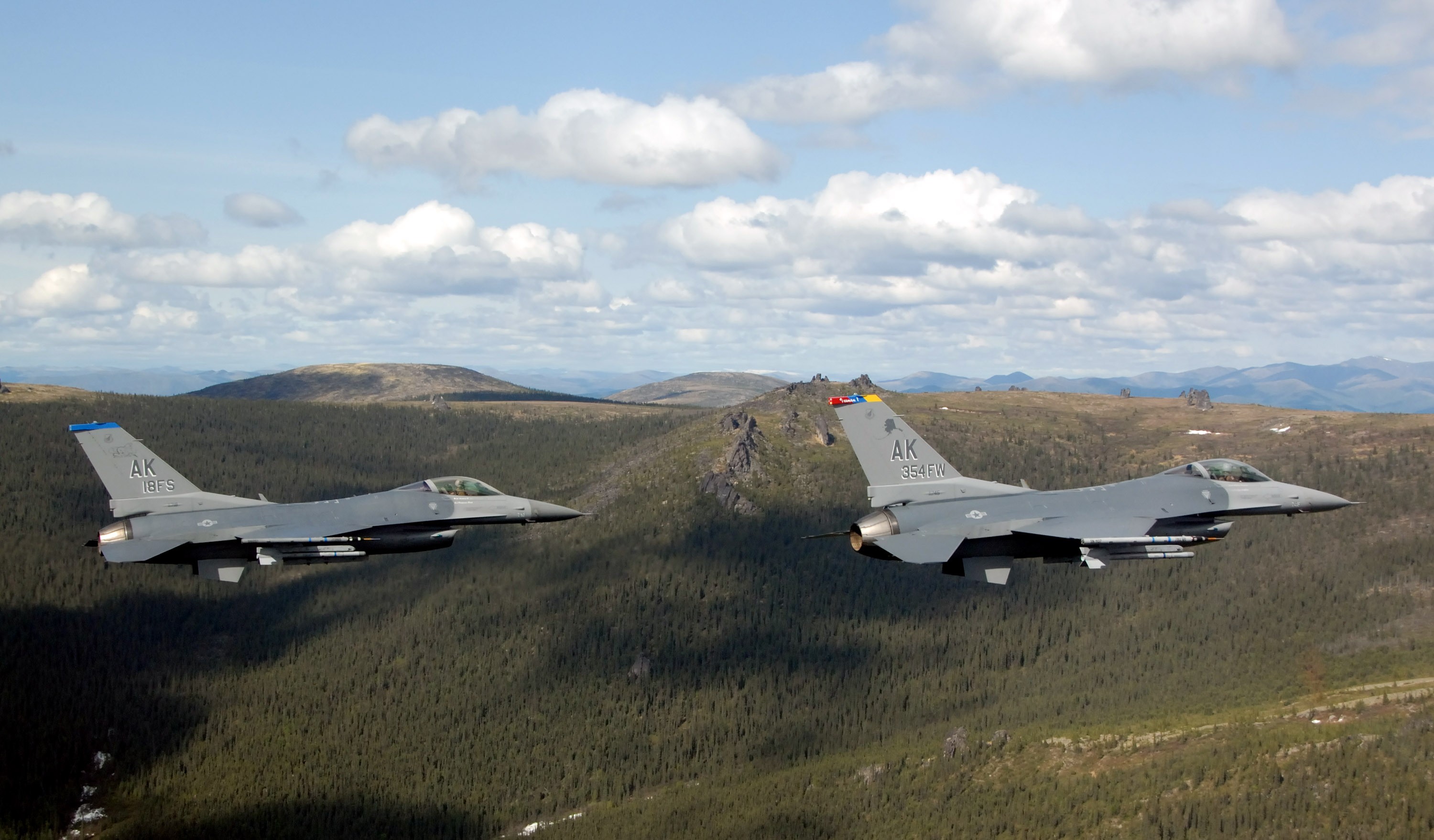 Two fighter jets flying over mountains