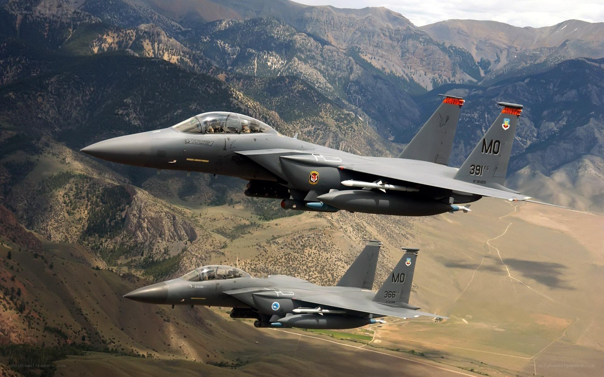 Two fighter jets flying over mountains