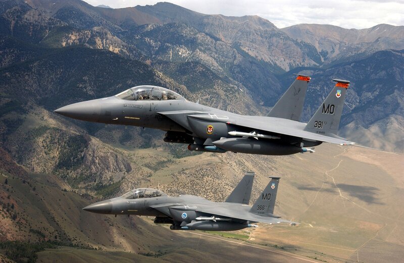 Two fighter jets flying over mountains