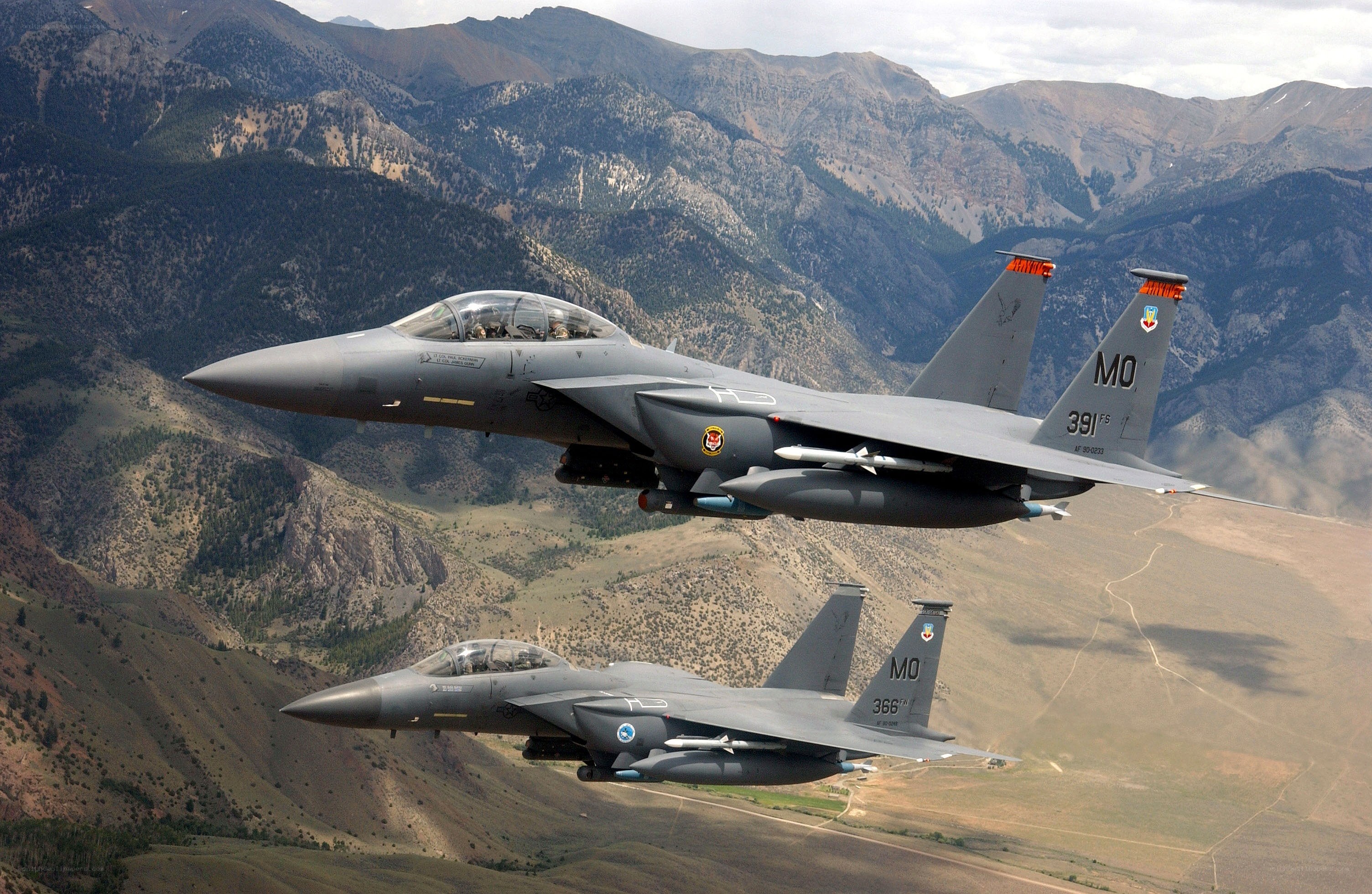 Two fighter jets flying over mountains