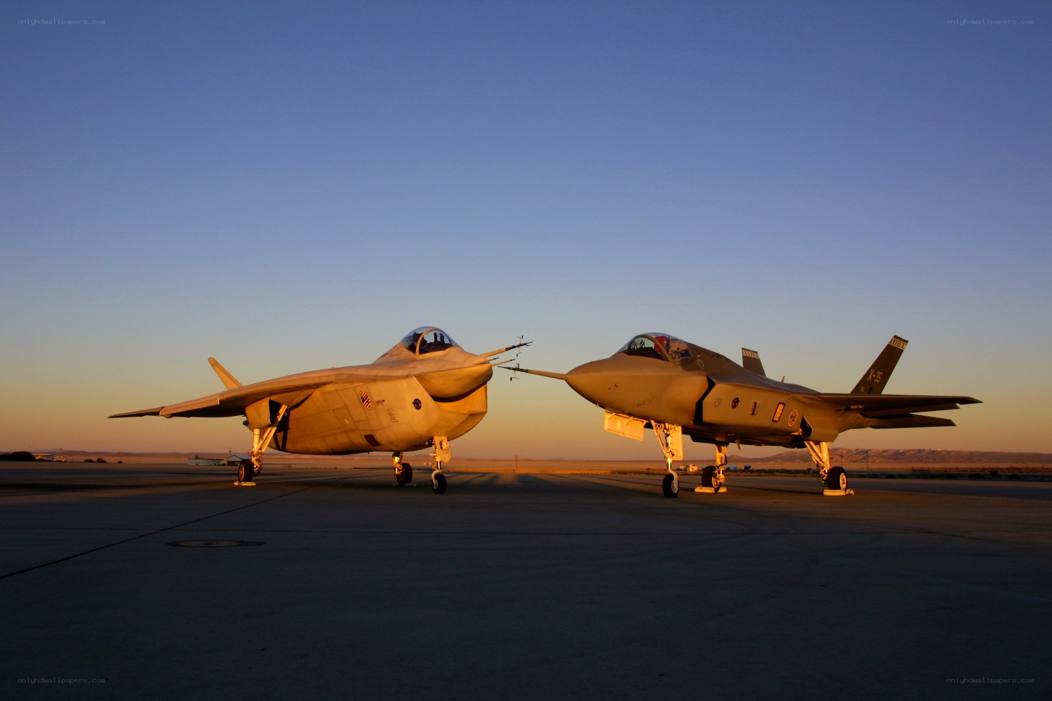 Two fighter jets on tarmac at sunset