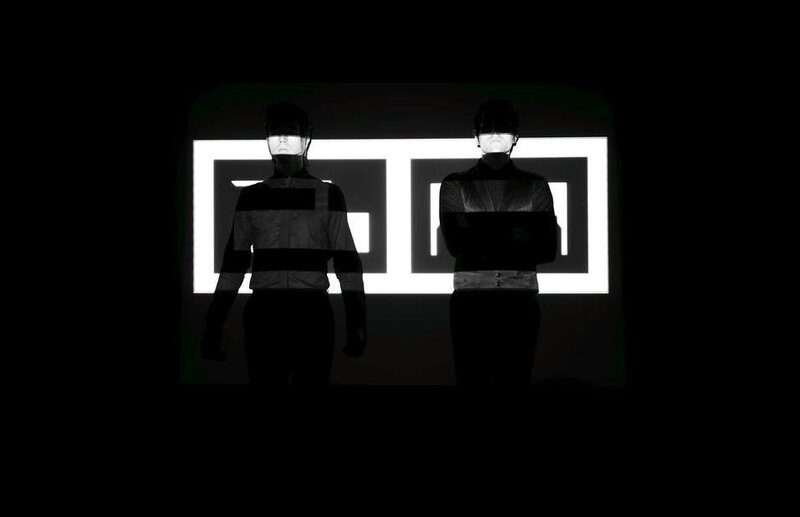 Two figures in front of a glowing sign