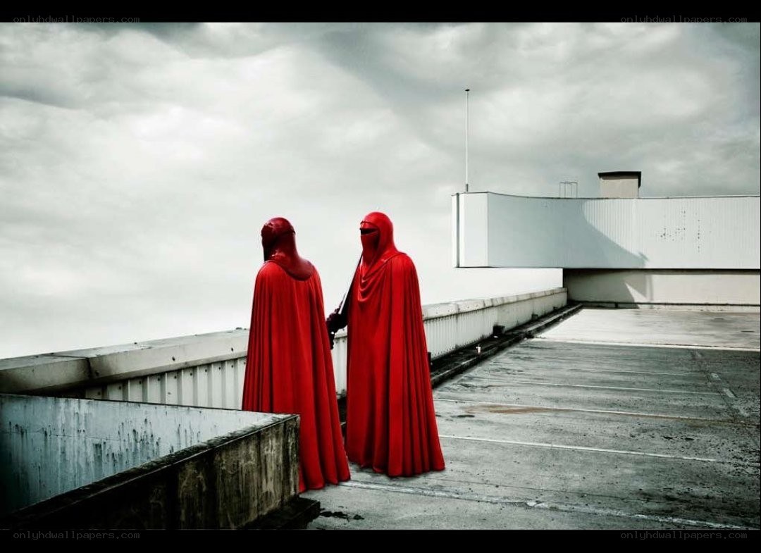 Two figures in red cloaks on a rooftop