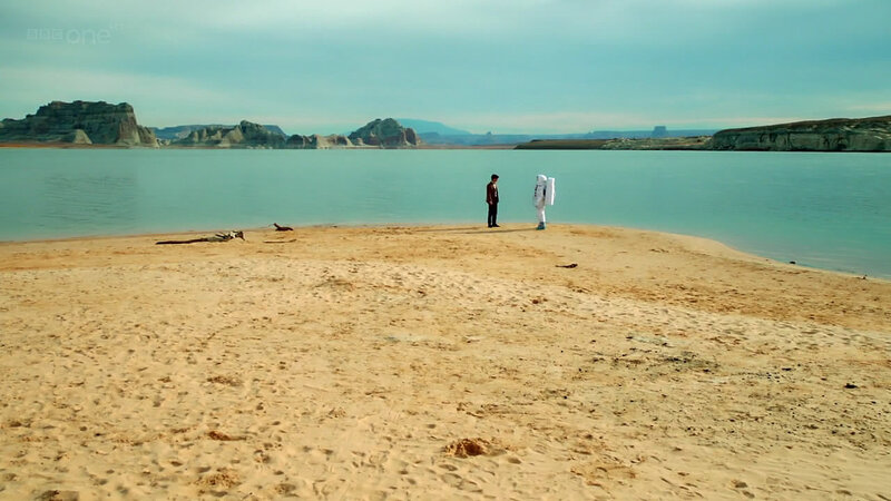 two figures on a desert beach