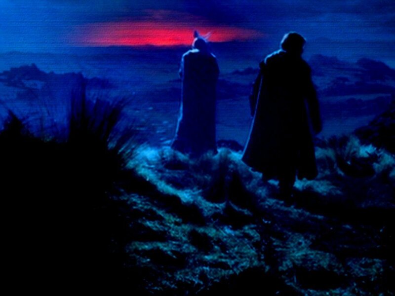 two figures on a hill at dusk