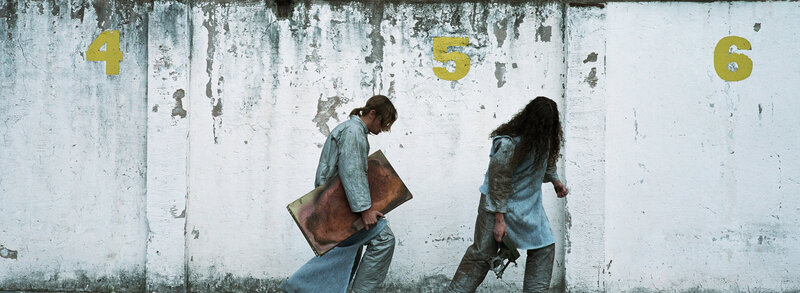 Two figures walk past numbered wall