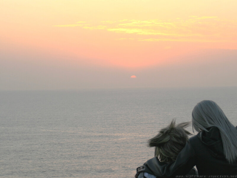 two figures watching sunset over sea