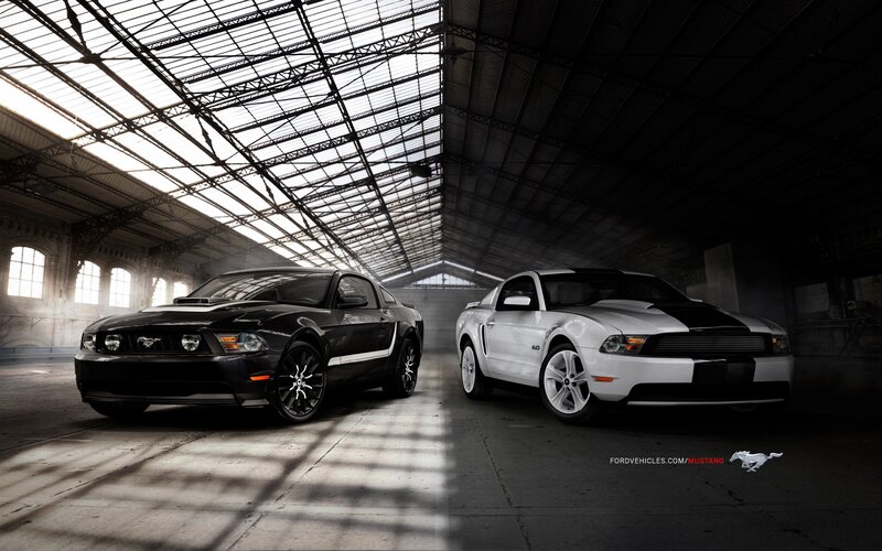 Two Ford Mustangs in a warehouse