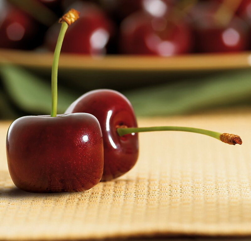 Two fresh cherries on a mat