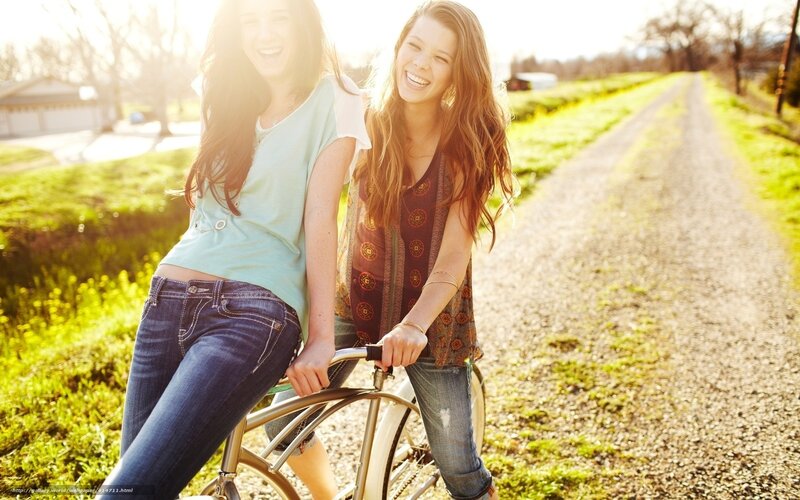 Two friends laughing on a bike