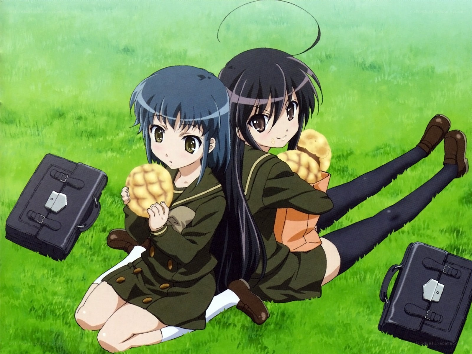 Two girls eating buns on grass