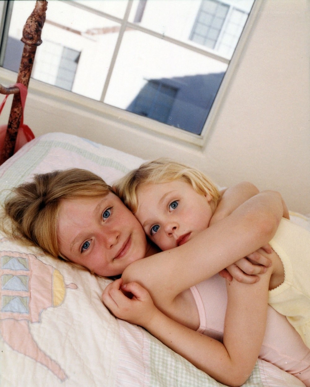 two girls hugging on a bed