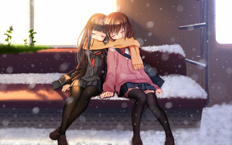 Two girls hugging on a snowy bench