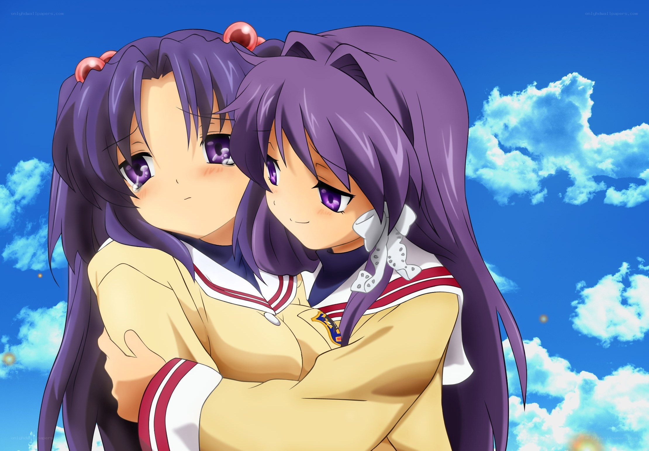 Two girls hugging under blue sky