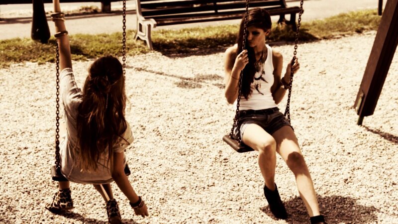 Two girls on swings at a park